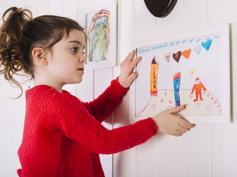 Niña colgando su dibujo